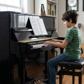 Boy practicing piano in home music room.