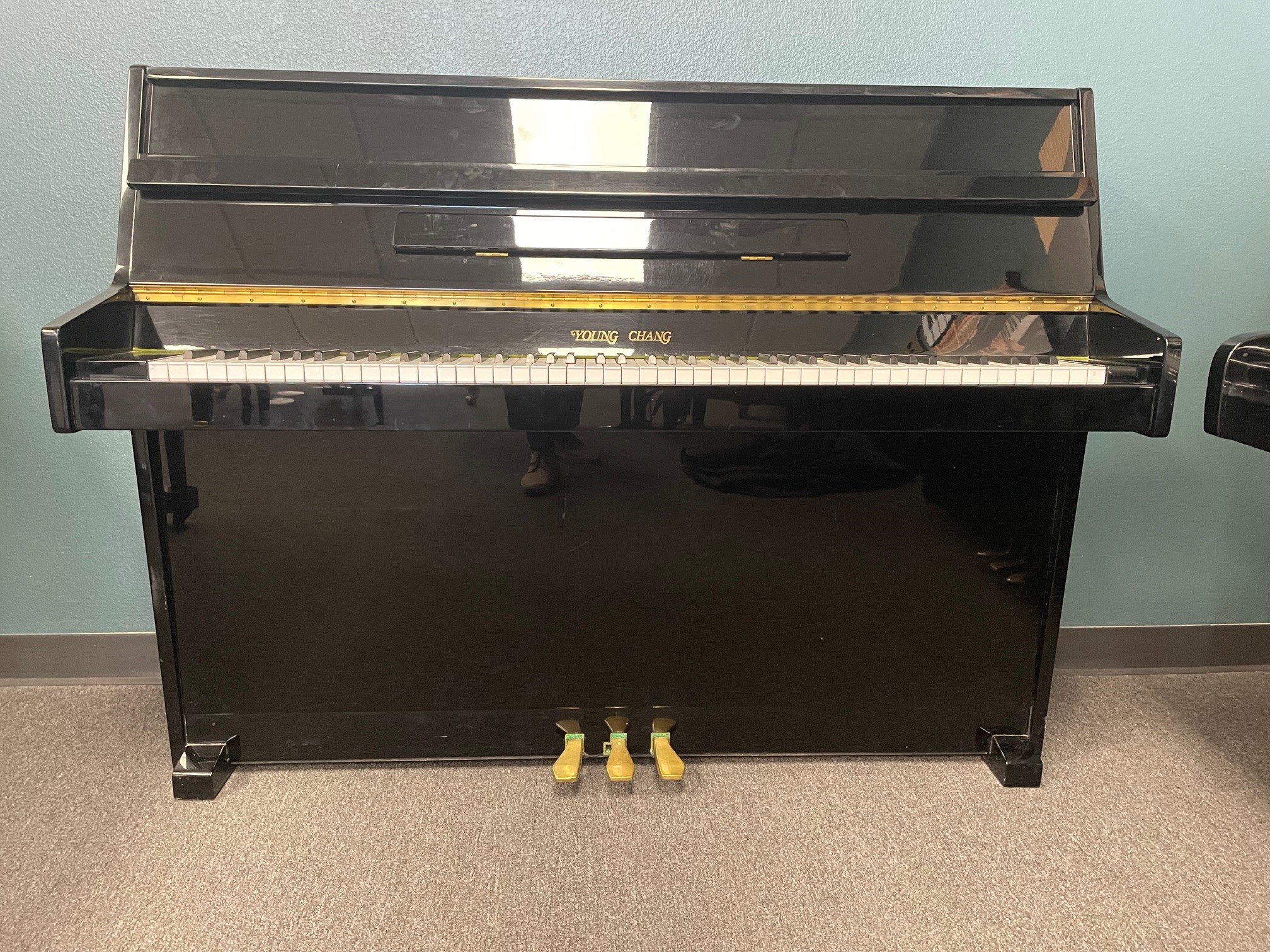 Black upright piano against blue wall